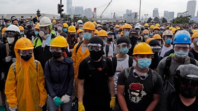 In this photo taken on Wednesday, June 12, 2019, protestors wear masks and helmets to protect their identities near the Legislative Council in Hong Kong.