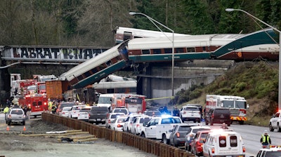 In this Dec. 18, 2017, file photo, cars from an Amtrak train lay spilled onto Interstate 5 below as some remain on the tracks above in DuPont, Wash. The National Transportation Safety Board has published its final report Monday, June 24, 2019, on a deadly Amtrak derailment in Washington state in 2017, with the agency's vice chairman blasting what he described as a 'Titanic-like complacency' among those charged with ensuring train operations are safe. The train was on its first paid passenger run on a new route from Tacoma to Portland, Oregon, when it plunged onto Interstate 5, killing three people and injuring dozens.