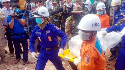 In this photo provided by Preah Sihanouk Provincial Authority, rescuers carry the body of a victim at the site of a building collapse, Monday, June 24, 2019, in Preah Sihanouk province, Cambodia. Rescuers on Monday continued to search the rubble of a building that collapsed while under construction in a Cambodian beach town, killing over two dozen workers and injuring 24 others as they slept in the unfinished condominium that was doubling as their housing.