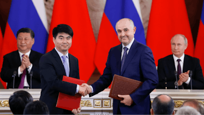 Guo Ping, deputy Chairman of Huawei Technologies Co Ltd, foreground left, shakes hands with Russian President of MTS mobile network operator, Alexei Kornya as Russian President Vladimir Putin, right, and Chinese President Xi Jinping attend a signing ceremony following their talks in the Kremlin in Moscow, Russia, Wednesday, June 5, 2019. Chinese President Xi Jinping is on visit to Russia this week and is expected to attend Russia's main economic conference in St. Petersburg.