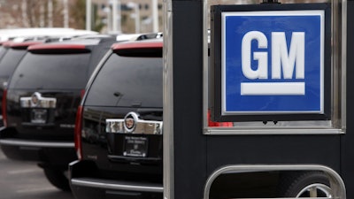 In this Sunday, Dec. 7, 2008, file photo, a GM sign in front of unsold 2009 Escalades at a Cadillac dealership in Lone Tree, Colo.