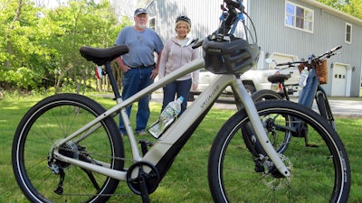 In this June 8, 2019 photo, Gordon and Janice Goodwin show their electric-assist bicycles outside their home in Bar Harbor, Maine. The bikes are banned on carriage roads and bicycle paths in nearby Acadia National Park.