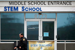 In this Wednesday, May 8, 2019, file photo, a Douglas County, Colo., Sheriff's Department deputy walks past the doors to the STEM School Highlands Ranch, in Highlands Ranch, Colo. A high school student charged in a classmate’s death during a shooting at the school told police that he planned the shooting for a few weeks and intended to target classmates who made fun of his gender identity.