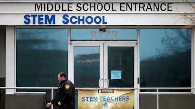 In this Wednesday, May 8, 2019, file photo, a Douglas County, Colo., Sheriff's Department deputy walks past the doors to the STEM School Highlands Ranch, in Highlands Ranch, Colo. A high school student charged in a classmate’s death during a shooting at the school told police that he planned the shooting for a few weeks and intended to target classmates who made fun of his gender identity.