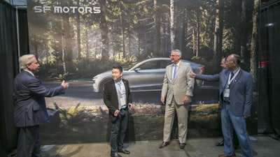 SF Motors CEO John Zhang, second from left, and Indiana Gov. Eric Holcomb, second from right, pose for picture in front of a mural of the SF 7, the company's electric vehicle, on Wednesday, May 30, 2018, in Mishawaka, Ind.
