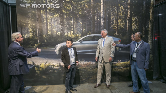 SF Motors CEO John Zhang, second from left, and Indiana Gov. Eric Holcomb, second from right, pose for picture in front of a mural of the SF 7, the company's electric vehicle, on Wednesday, May 30, 2018, in Mishawaka, Ind.