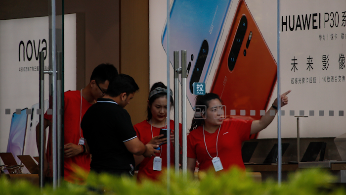 Staffers help a tourist search for directions at a Huawei retail store in Beijing, Tuesday, June 11, 2019.