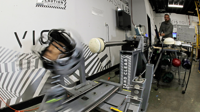 In this photo taken May 23, 2019, Ryan Smith, a test engineer at VICIS, a Seattle-based company that makes football helmets, runs an impact test on a helmet in Seattle. The company's latest offering is the ULTIM cap, which is intended for use with youth flag football and competitive 7-on-7 football played during the offseason for youth and high school programs.