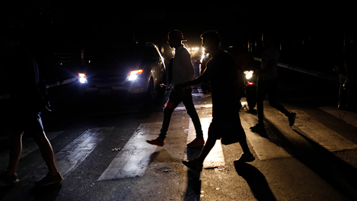 In this Monday, July 22, 2019, file photo, people walk on a street during a blackout in Caracas.