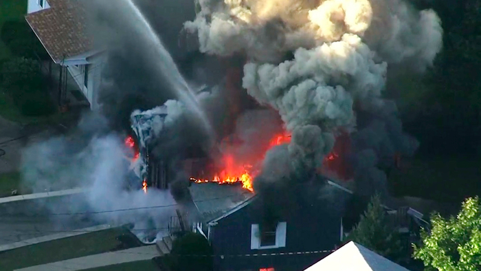 In this Sept. 13, 2018 file image from video provided by WCVB in Boston, flames consume the roof of a home following an explosion in Lawrence, Mass. Columbia Gas of Massachusetts and its parent, NiSource Inc., announced Monday, July 29, 2019, a settlement had been reached in class action lawsuits resulting from the disaster across several towns north of Boston.