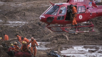In this Jan. 28, 2019, file photo, firefighters prepare a body to be lifted away by a helicopter, after pulling the dead person from the mud days after a dam collapse in Brumadinho, Brazil.