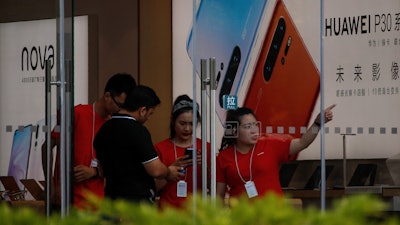 Staffers help a tourist search for directions at a Huawei retail store in Beijing, Tuesday, June 11, 2019.