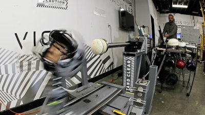 In this photo taken May 23, 2019, Ryan Smith, a test engineer at VICIS, a Seattle-based company that makes football helmets, runs an impact test on a helmet in Seattle. The company's latest offering is the ULTIM cap, which is intended for use with youth flag football and competitive 7-on-7 football played during the offseason for youth and high school programs.