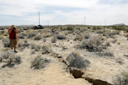 A visitor takes a photo of a crack on the ground following recent earthquakes Sunday, July 7, 2019, outside of Ridgecrest, Calif.