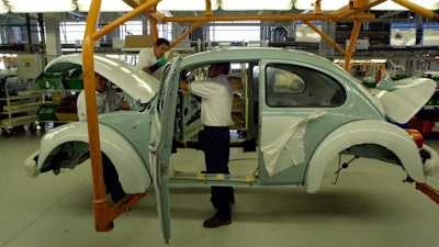 In this July 21, 2003, file photo, Volkswagen employees work in the assembly plant of the sedan 'last edition' in Puebla, Mexico.