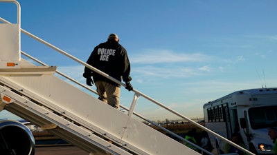 In this Nov. 16, 2018, file photo, an officer watches as immigrants who entered the United States illegally are deported on a flight to El Salvador by U.S. Immigration and Customs Enforcement in Houston.