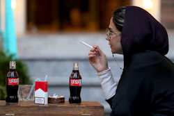 An Iranian smokes a Marlboro cigarette while two Coca-Cola stand on her table at a cafe in downtown Tehran, Wednesday, July 10, 2019.