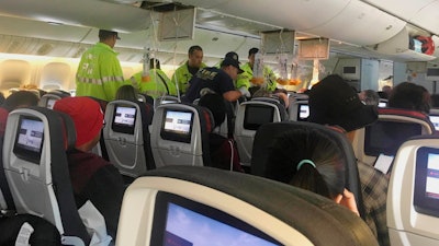 In this Thursday, July 11, 2019, photo, provided by Tim Tricky of the band Hurricane Fall, emergency workers treat a passenger on an Air Canada flight to Australia that was diverted and landed at Daniel K. Inouye International Airport in Honolulu.