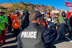 A police officer gestures at demonstrators blocking a road at the base of Hawaii's tallest mountain, Monday, July 15, 2019, in Mauna Kea, Hawaii.