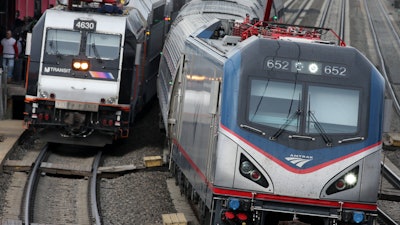 In this March 12, 2016, file photo, an Amtrak train passes a New Jersey Transit train in Elizabeth, N.J.