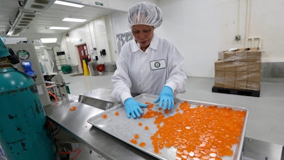 Ioka Tasi works on packaging cannabis-infused mango hard candies at Evergreen Herbal, Wednesday, July 24, 2019, in Seattle.