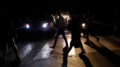 In this Monday, July 22, 2019, file photo, people walk on a street during a blackout in Caracas.