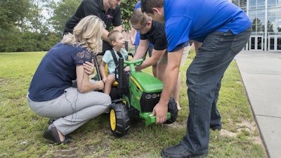 Four-year-old Jack Carroll looks up at the UWF engineering students as they help him into a vehicle that they modified for him at University of West Florida's Hal Marcus College of Science and Engineering in Pensacola on Wednesday, July 17, 2019. The modified vehicle will help Jack's mobility that is reduced due to cerebral palsy.