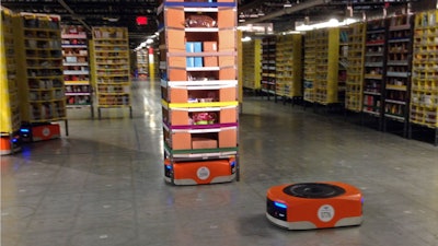 A robot moves under a stack of merchandise during a tour of an Amazon facility in Tracy, Calif., Nov. 30, 2014.