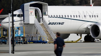 In this March 14, 2019, file photo, a worker walks next to a Boeing 737 MAX 8 airplane parked at Boeing Field in Seattle. Flyadeal, a Saudi budget carrier says it is ordering 30 new Airbus planes, replacing a $6 billion agreement it had with Boeing for its troubled 737 MAX jets, which are grounded around the world after two crashes.