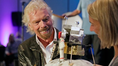 Richard Branson is presented with a space-themed cake during a luncheon attended by 100 Virgin Galactic ticket holders, to mark his 69th birthday and in recognition of the Apollo 11 moon landing anniversary at the Kennedy Space Center Visitor Complex, Thursday, July 18, 2019, in Cape Canaveral, Fla.