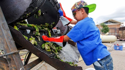 In this Aug. 9, 2017, file photo, Chris Duran Jr, 7 helps roast green chile with his family outside the Big Lots in Santa Fe, N.M. A hybrid version of a New Mexico chile plant has been selected to be grown in space as part of a NASA experiment, officials recently announced.