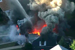 In this Sept. 13, 2018 file image from video provided by WCVB in Boston, flames consume the roof of a home following an explosion in Lawrence, Mass. Columbia Gas of Massachusetts and its parent, NiSource Inc., announced Monday, July 29, 2019, a settlement had been reached in class action lawsuits resulting from the disaster across several towns north of Boston.
