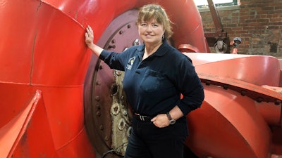 In this June 5, 2019 photo, Natural Power Group co-owner Sarah Bower-Terbush stands in front of a power turbine at the company's hydroelectric site in Wappingers Falls, N.Y. She and her husband sell renewable power to local customers from three hydroelectric sites they operate in the Hudson Valley. Customers say they like investing their money locally in clean power.