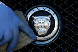 In this file photo dated Wednesday, Sept. 28, 2016, a worker polishes a Jaguar logo on a car at a Jaguar dealer outlet in London. Jaguar Land Rover has announced Friday July 5, 2019, it will retool with new equipment at Castle Bromwich, in central England, to manufacture an all-electric version of the Jaguar XJ sedan car in the U.K.