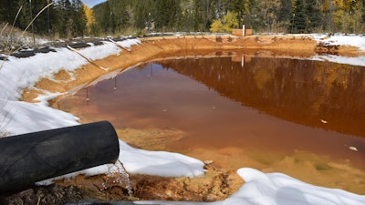 In this Oct. 12, 2018, file photo, water contaminated with arsenic, lead and zinc flows from a pipe out of the Lee Mountain mine and into a holding pond near Rimini, Mont. An appeals court Friday, July 19, 2019, has sided with the Trump administration after it dropped a proposal that would have required mining companies to prove they have the wherewithal to clean up future pollution.