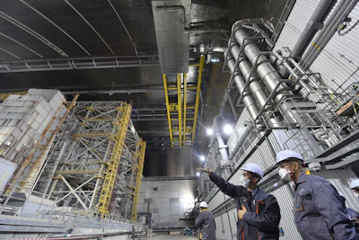 In this June 1, 2019, file photo, French Foreign Minister Jean-Yves Le Drian, right, listens to an employee inside the New Safe Confinement (NSC) movable enclosure at the nuclear power plant in Chernobyl, Ukraine. A new structure built to confine the Chernobyl reactor at the center of the world's worst nuclear disaster was previewed for the media Tuesday, July 2.