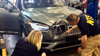 In this March 20, 2018, file photo, provided by the National Transportation Safety Board, investigators examine a driverless Uber SUV that fatally struck a woman in Tempe, Ariz. Police outside Phoenix recently closed part of a street to conduct a lighting test as an investigation continues into the 2018 death of a woman who was struck and killed by an Uber self-driving SUV. The Maricopa County Attorney’s Office says prosecutors asked for more investigation before making a decision about whether to charge backup driver Rafaela Vasquez who was supposed to take control in an emergency. Another prosecutor’s office decided in March not to charge Uber.