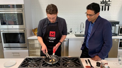 In this photo taken April 11, 2019, Memphis Meats CEO Uma Valeti, right, watches chicken produced in a laboratory from chicken cells being cooked in Emeryville, Calif. The company is focused on reducing the cost of cultured meat and producing larger quantities. A plate of chicken that used to cost tens of thousands of dollars to produce can now be made for less than $100, Valeti said.