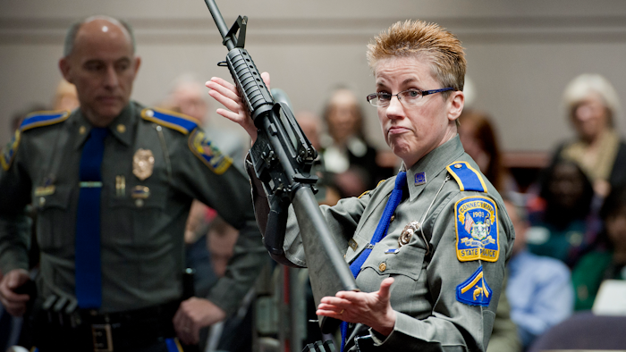 In this Jan. 28, 2013, file photo, firearms training unit Detective Barbara J. Mattson of the Connecticut State Police holds up a Bushmaster AR-15 rifle during a hearing of a legislative subcommittee in Hartford, Conn.