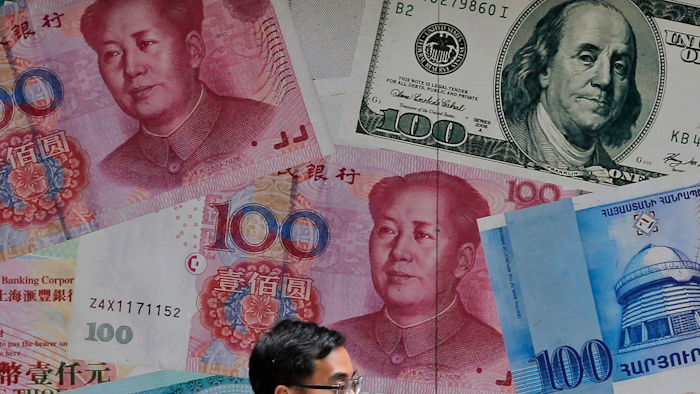 In this June 10, 2019, file photo, a man walks past a money exchange shop decorated with different banknotes at Central, a business district of Hong Kong.