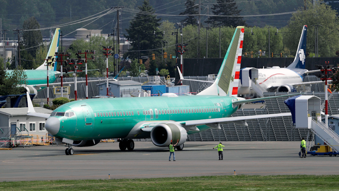 In this Wednesday, May 8, 2019 file photo, workers stand near a Boeing 737 MAX 8 jetliner being built for American Airlines prior to a test flight in Renton, Wash. Federal safety officials are recruiting pilots from airlines around the world to test changes that Boeing is making in flight-control software on the grounded 737 Max jet, according to two people briefed on the situation.