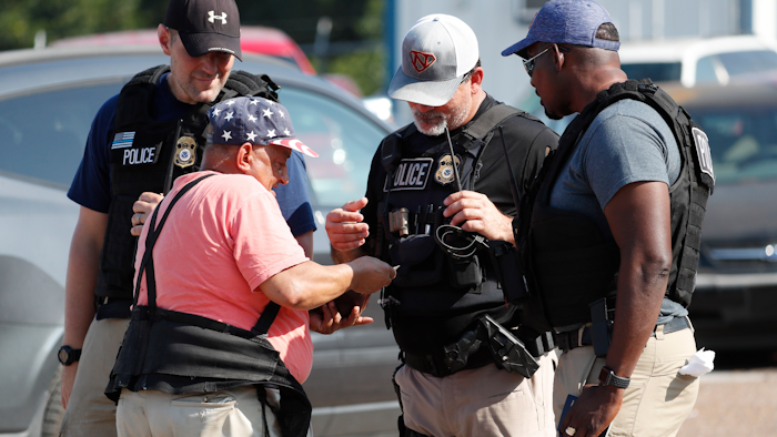 Domingo Candelaria, a registered immigrant, shows federal agents his identification as he prepares to leave the Koch Foods Inc., plant in Morton, Miss., following a raid by U.S. immigration officials, Wednesday, Aug. 7, 2019. The raid, one of several in Mississippi, was part of a large-scale operation targeting owners as well as undocumented employees.