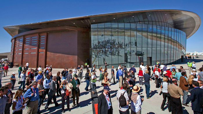 In this Oct. 17, 2011 file photo, guests stand outside the new Spaceport America hangar in Upham, N.M. Virgin Galactic is scheduled to unveil the interior of its digs at Spaceport America, providing the first glimpse of mission control, a prep area for pilots and where paying customers will lounge ahead of their suborbital flights. Company officials are gathering Thursday, Aug. 15, 2019, at the remote facility in the New Mexico desert to show off two levels of the custom-tailored hangar at the taxpayer-financed spaceport.
