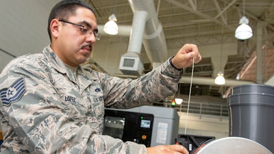 U.S. Air Force Tech. Sgt. Rogelio Lopez, 60th Maintenance Squadron assistant aircraft metals technology section chief, loads Ultem 9085 material into a canister for use in the Stratasys F900 three-dimensional printer, Aug. 15, 2019, Travis Air Force Base, Calif.