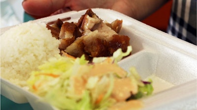 In this Thursday, March 14, 2019, photo, Belinda Lau, manager of the Wiki Wiki Drive Inn takeout restaurant in Honolulu, holds a polystyrene foam box containing an order of roast pork, rice and salad.