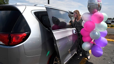 In this Tuesday, July 16, 2019, Melanie Matcheson loads balloons into her Chrysler Pacifica in Southington, Conn.