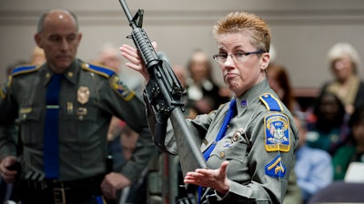 In this Jan. 28, 2013, file photo, firearms training unit Detective Barbara J. Mattson of the Connecticut State Police holds up a Bushmaster AR-15 rifle during a hearing of a legislative subcommittee in Hartford, Conn.