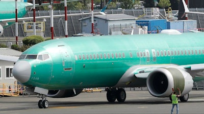 In this May 8, 2019, file photo, a worker stands near a Boeing 737 Max 8 jetliner prior to a test flight in Renton, Wash.