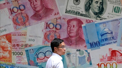 In this June 10, 2019, file photo, a man walks past a money exchange shop in Hong Kong.