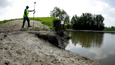 In this Tuesday, Aug. 6, 2019, photo, U.S. Army Corps of Engineers worker Ron Allen uses a GPS tool to survey the extent of damage where a levee failed along the Missouri River near Saline City, Mo.